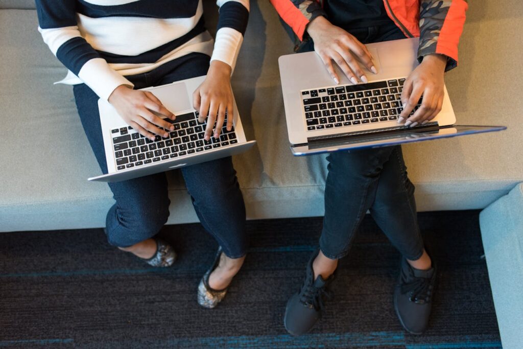 Two people working on laptops from above, showcasing collaboration in a tech environment.