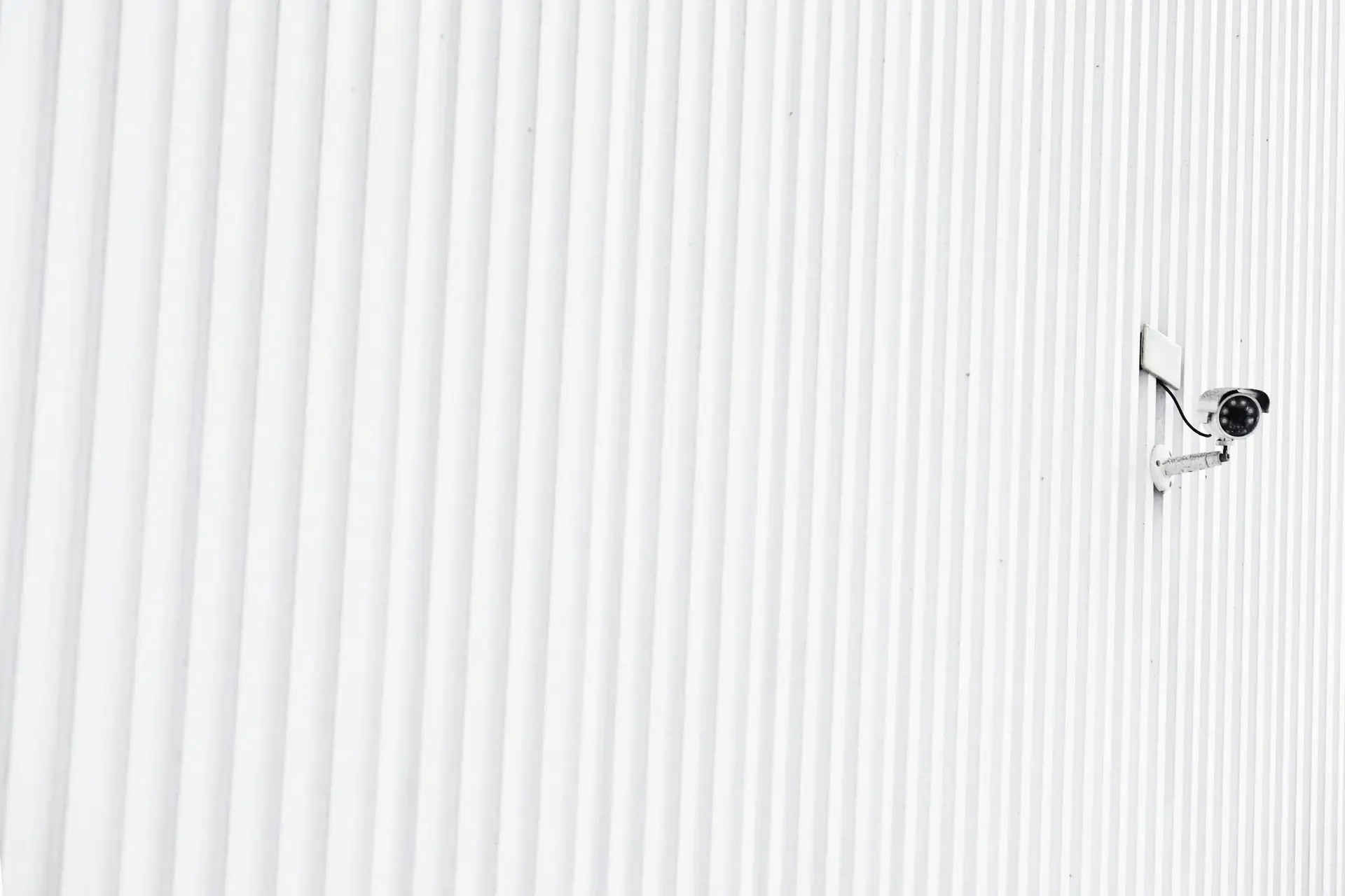 A minimalist photo of a security camera mounted on a corrugated wall, emphasizing privacy.